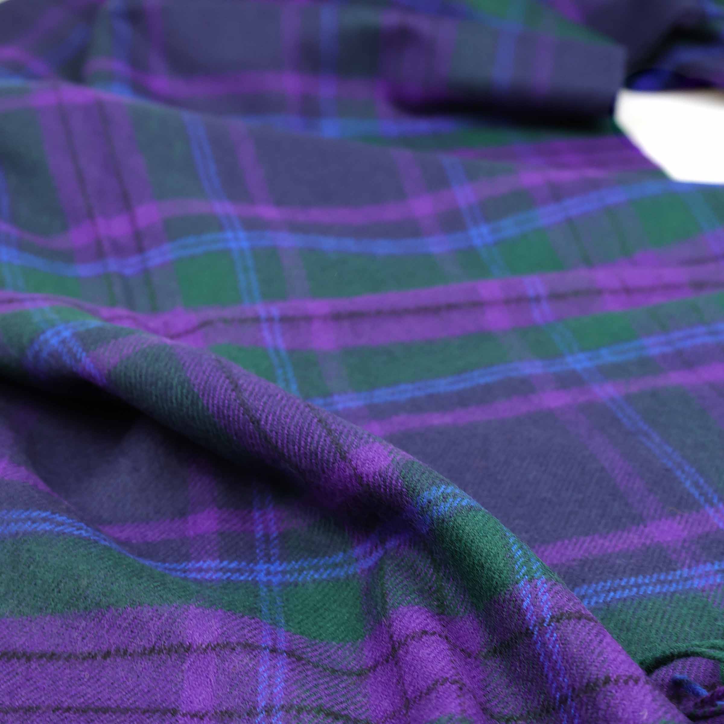 Lochcarron Wolldecke Spirit of Scotland Tartan — Lifestyle-Aufnahme, weicher Faltenwurf in Distel-Violett, Königsblau und Grün