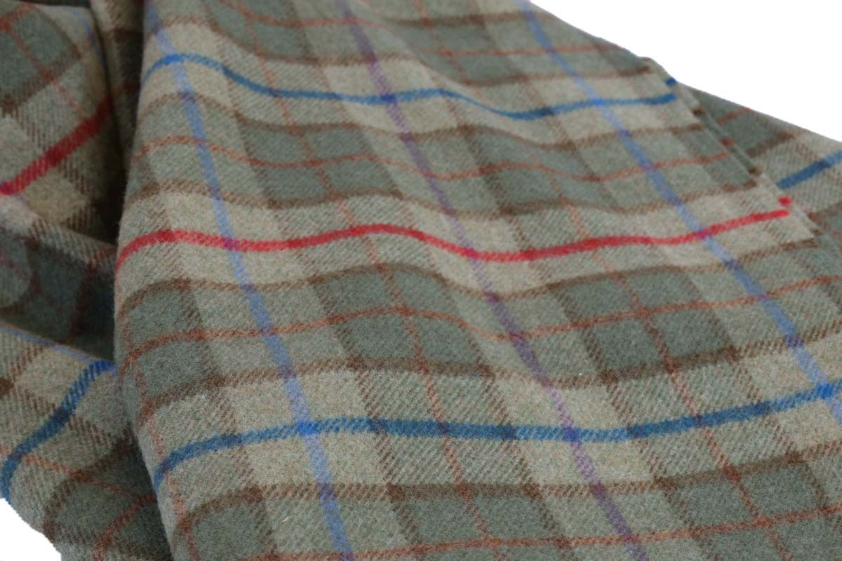 Schottische Tartan Wolldecke Ben Nevis – Grünes Karomuster aus 100 % Lammwolle auf einem Sofa drapiert
